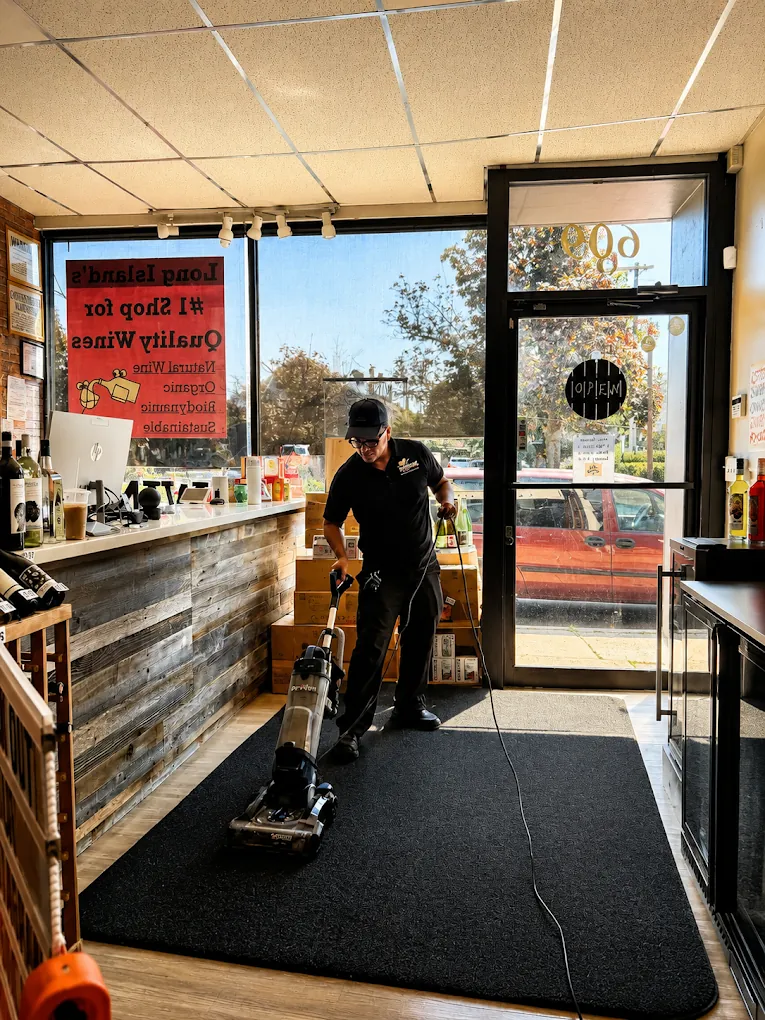 ISA Cleaning Services technician vacuuming the carpet of a Long Island retail store during commercial cleaning